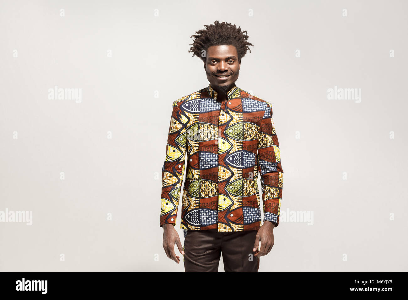 La felicità uomo africana in abiti tradizionali sorriso toothy. Indoor, isolata su uno sfondo grigio Foto Stock