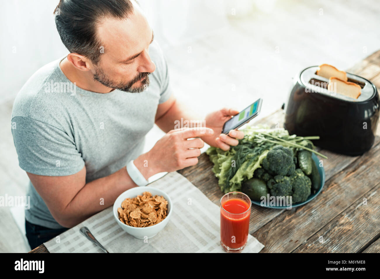 Attenzione concentrata l uomo con il suo cellulare preparando per mangiare. Foto Stock