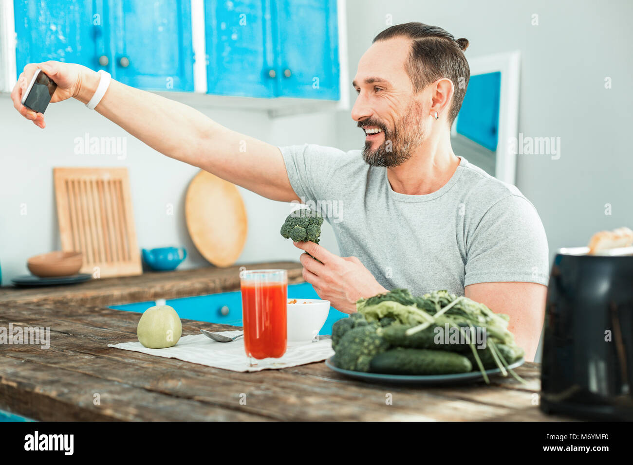 Piacevole uomo felice tenendo un broccoli e rendendo selfie. Foto Stock