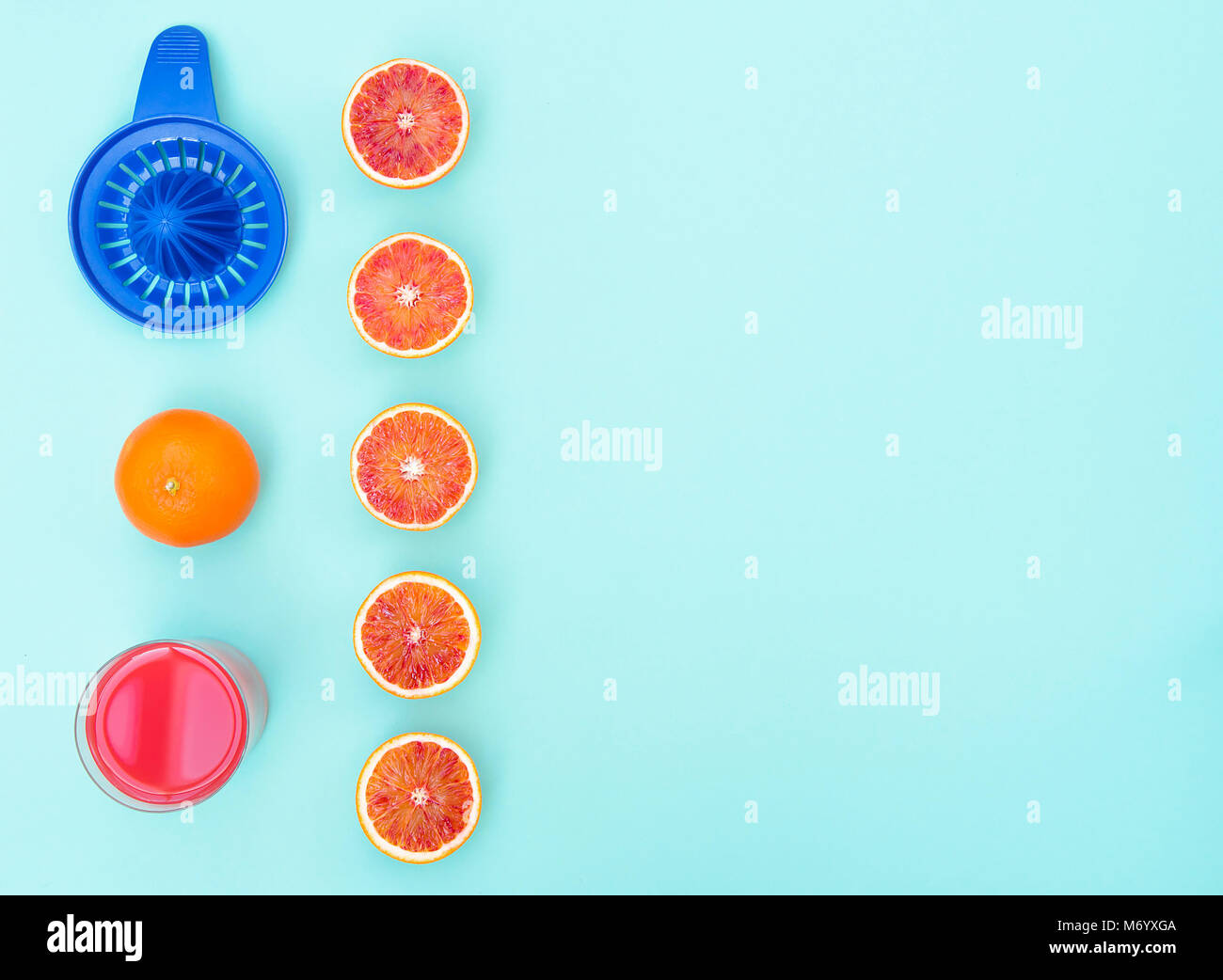 Vetro con fresche fatte succo di arance sanguigne sulla vibrante sfondo blu. Foto Stock