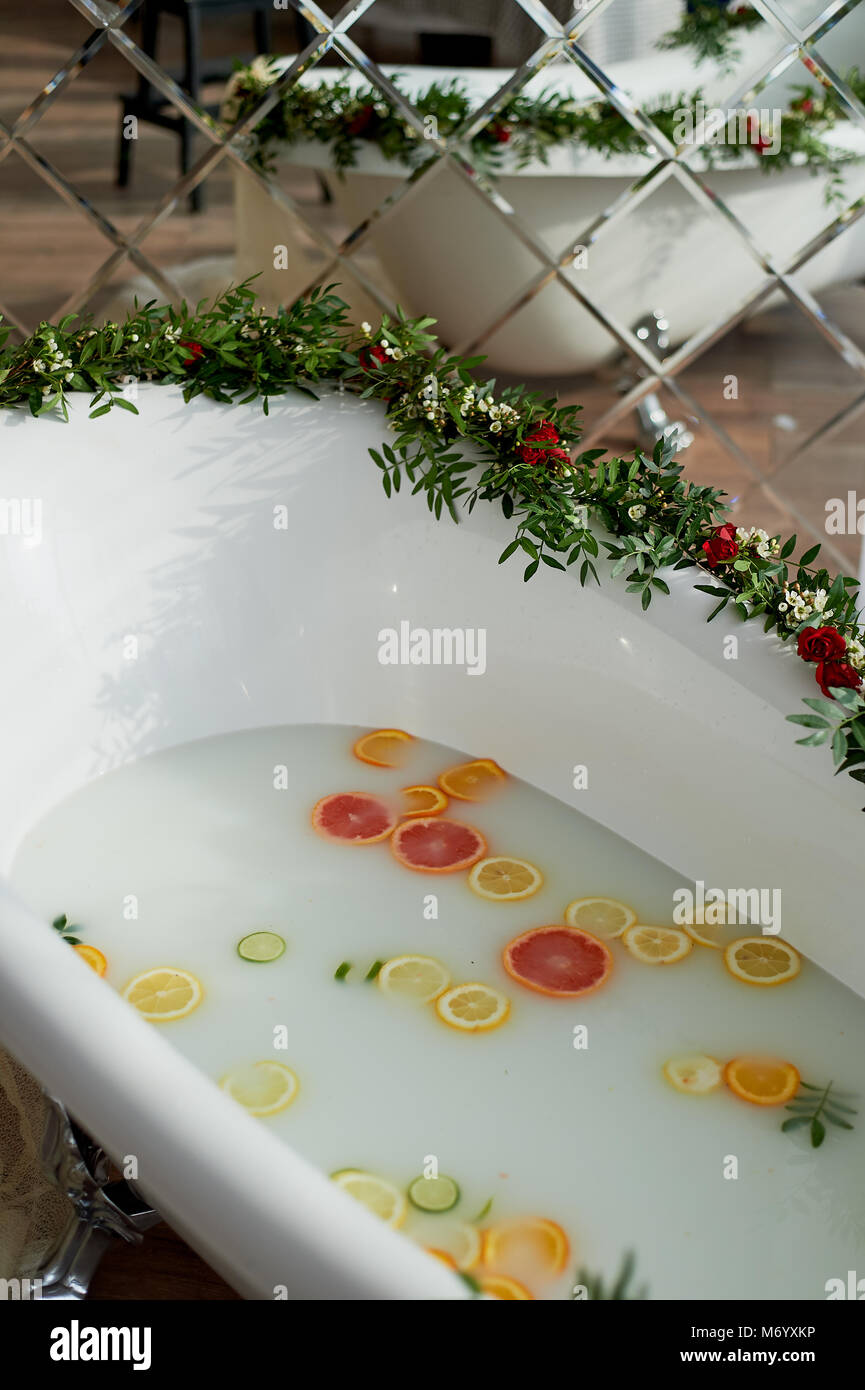 Elegante roll-top vasca da bagno e decorate con fiori. In acqua nuotare citrus.L'atmosfera di relax, relax Foto Stock