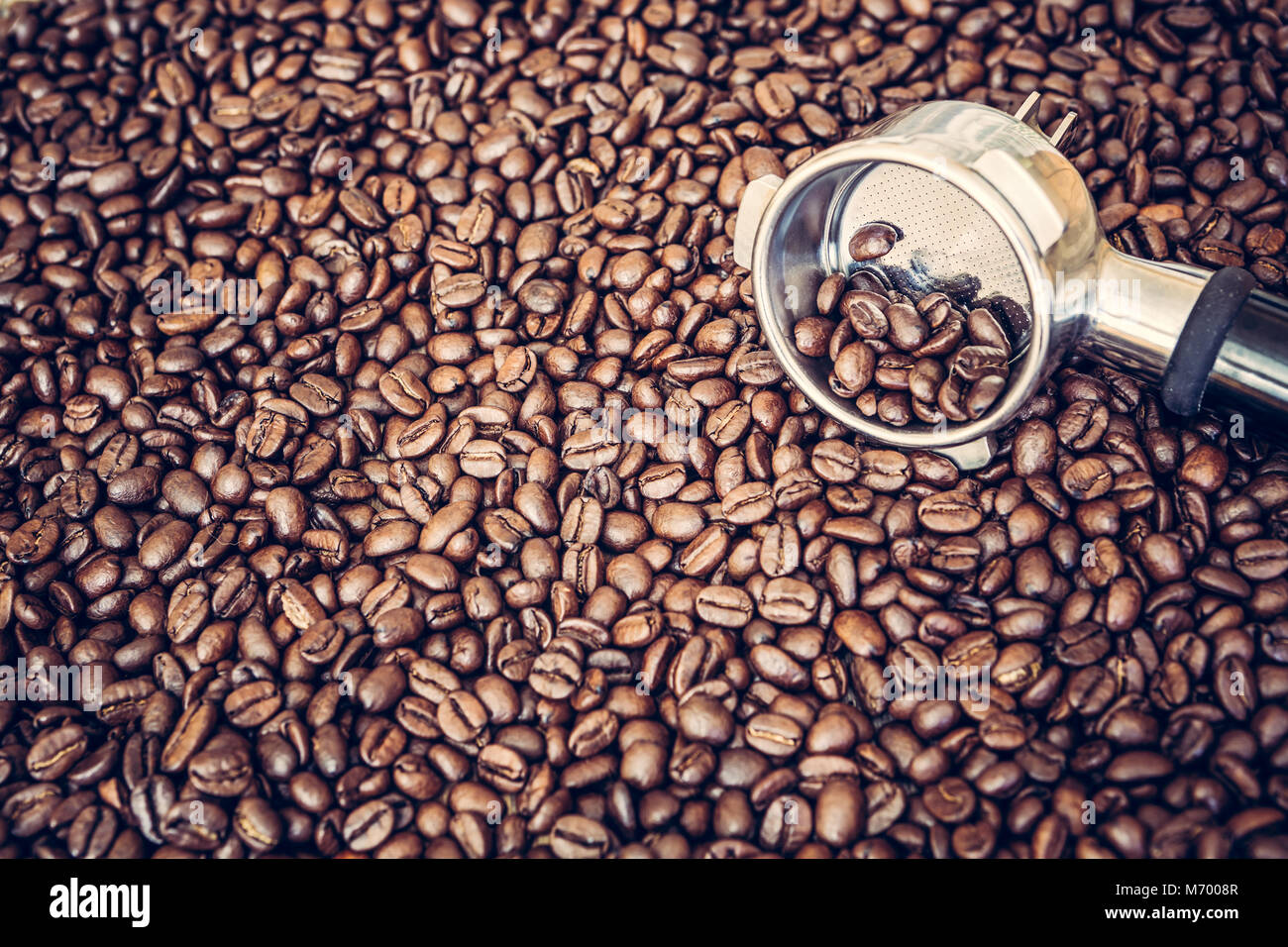 Metallo macchina espresso scoop su di chicchi di caffè tostati sfondo Foto Stock