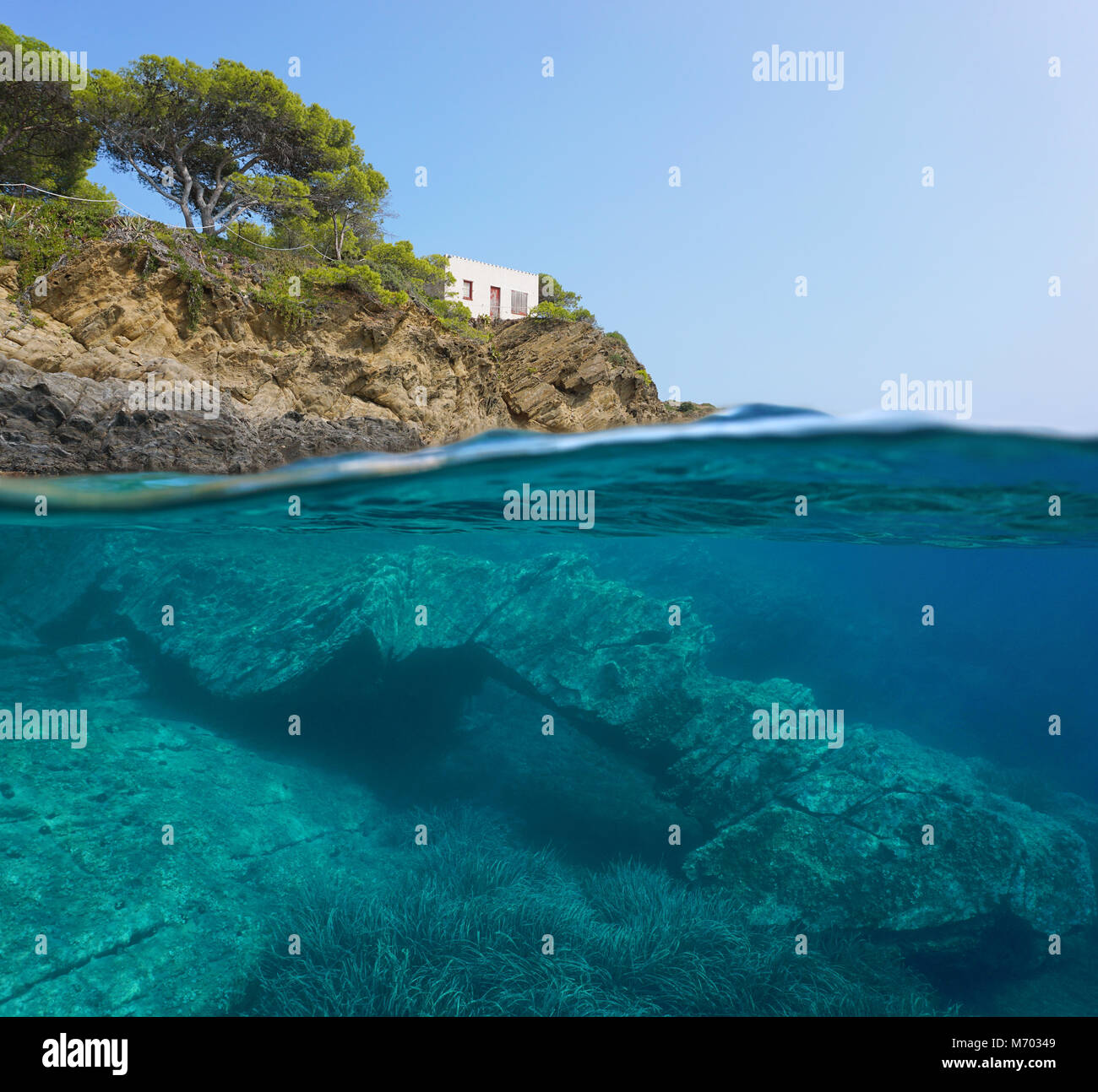 Spagna costa mediterranea con una piccola casa e una formazione rocciosa naturale subacquea, vista suddivisa al di sopra e al di sotto della superficie del mare, Catalonia, Costa Brava Foto Stock