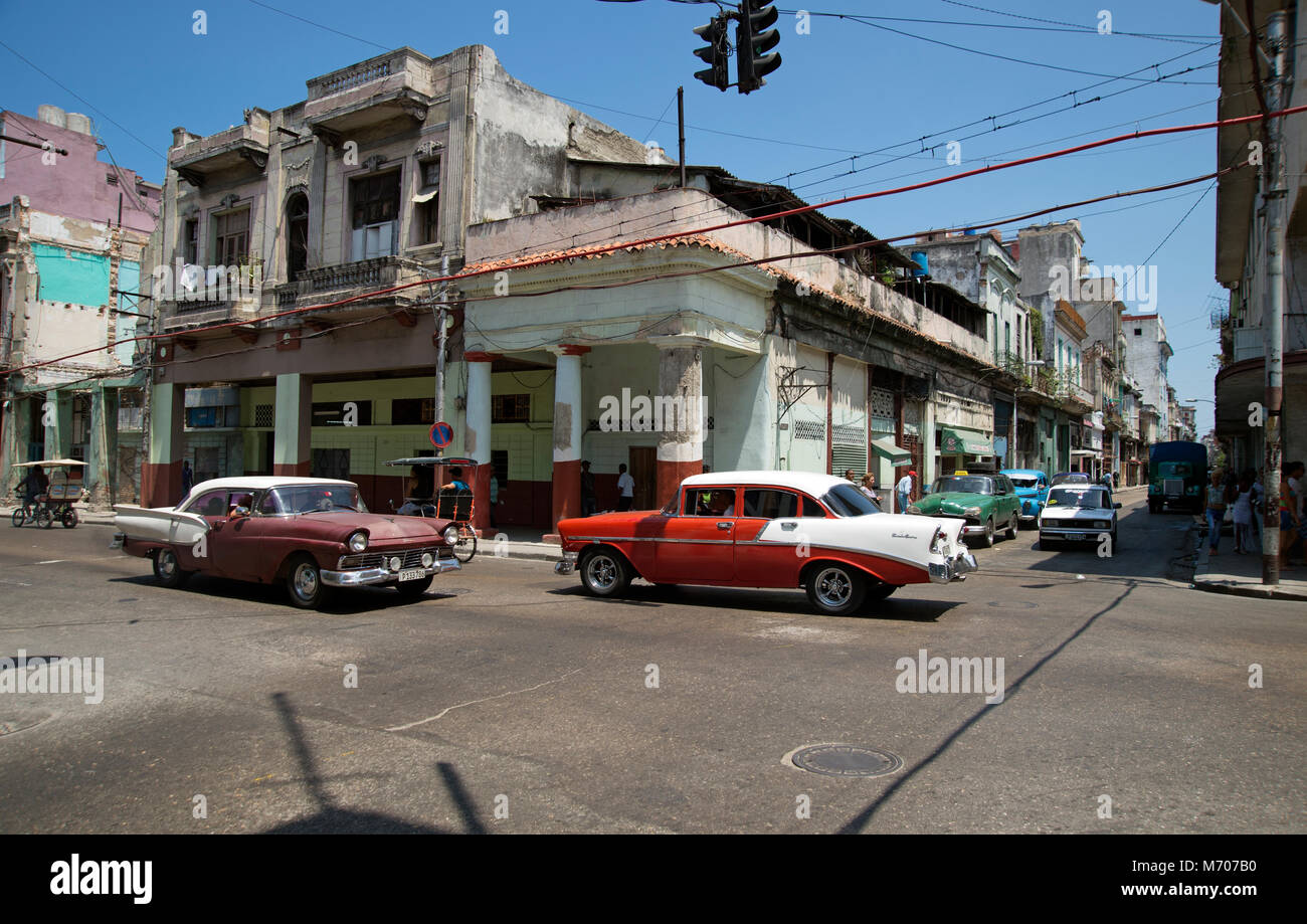 Due auto classiche restaurate dell'America Vecchia che guidano sulle strade trafficate del Centro Havana a Cuba Foto Stock