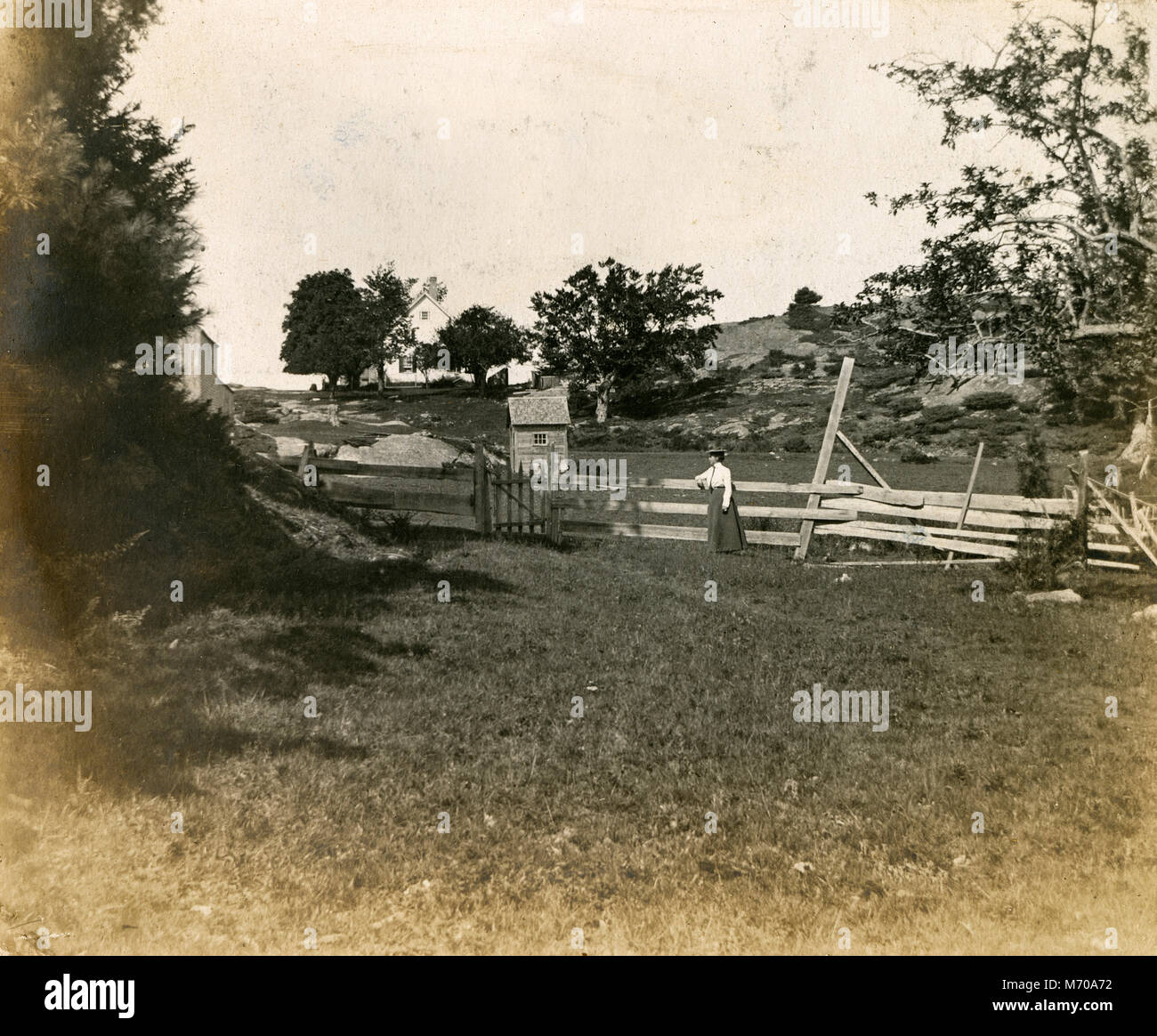 Antique circa 1905 fotografia, donna appoggiato su di una recinzione presso la sua proprietà. La posizione è in o vicino a Riggsville (ora Robinhood), Maine in Sagadahoc County, Stati Uniti d'America. Foto Stock