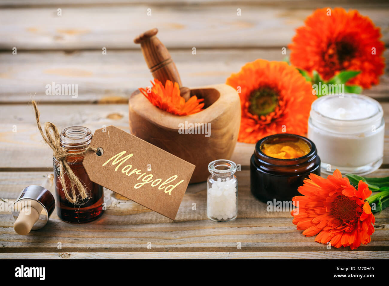Calendula o fiorrancio prodotti. Olio essenziale, globuli di omeopatia e cosmetici, tag con testo calendula. Tavolo in legno sfondo Foto Stock