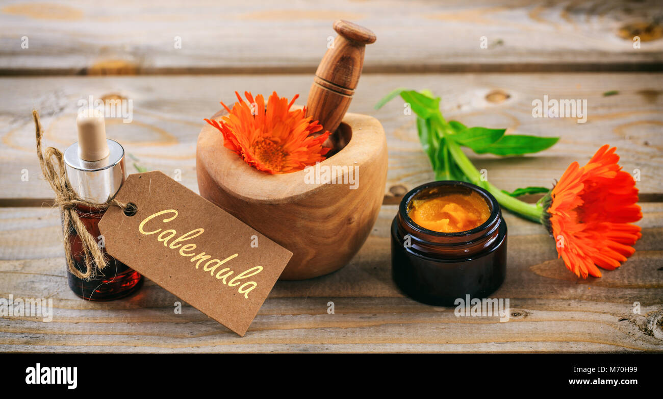 Calendula o fiorrancio aromaterapia. Olio essenziale e un unguento a base di erbe, testo calendula su un tag. Tavolo in legno sfondo Foto Stock
