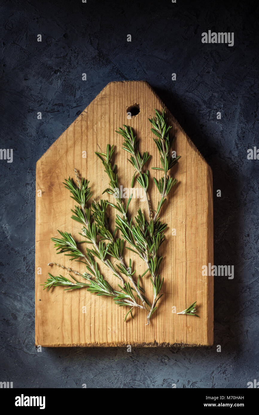 Il ramo mazzetto di rosmarino fresco concetto alimentare foraggio raccolto spezie Erbe per la medicina e la cottura sul tagliere Tasto scuro chiave di basso Foto Stock