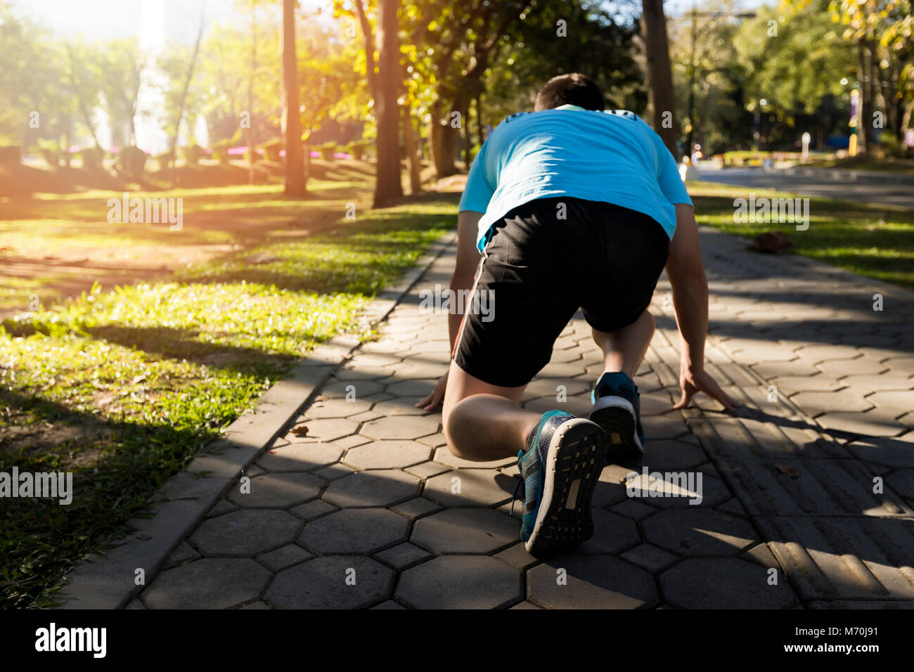 Pronti per andare! Close up tagliate ad angolo basso foto di scarpa di atleta uomo in esecuzione di avviare pongono sulla strada nel parco. Foto Stock