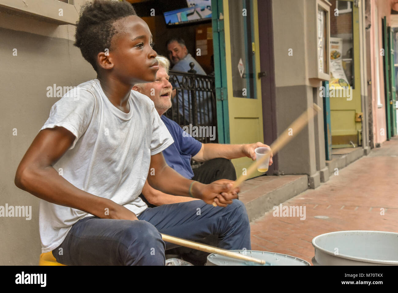 Si tratta di un giovane uomo su un angolo di strada di New Orleans utilizzando cinque galloni di secchi come tamburi divertente i passanti e la riproduzione per suggerimenti. Foto Stock