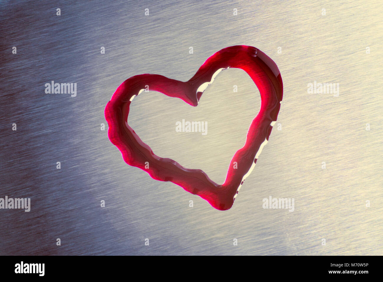 Gocce di colore rosso a forma di cuore. La superficie è metallico. Il giorno di San Valentino Foto Stock