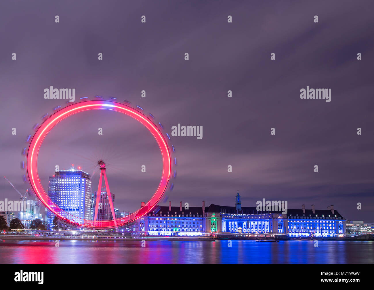 Il London Eye e County Hall illuminata di rosso e di blu su una torbida novembre serata. Foto Stock