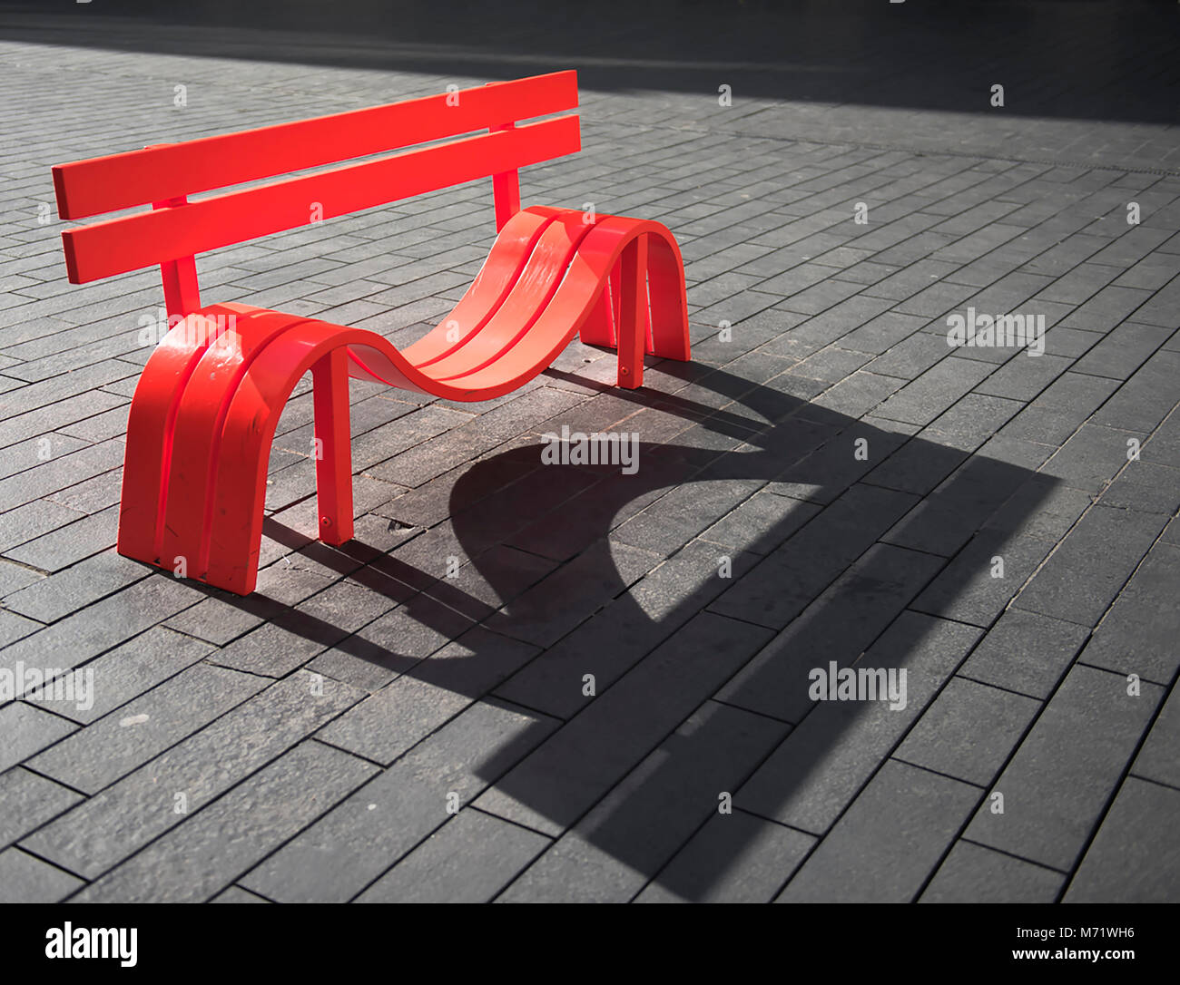 Arancione moderno banco di metallo, con dip in sede e di forte ombra. Questo sedile è parte di una serie di opere simili al di fuori del Festival Hall di Londra, Foto Stock