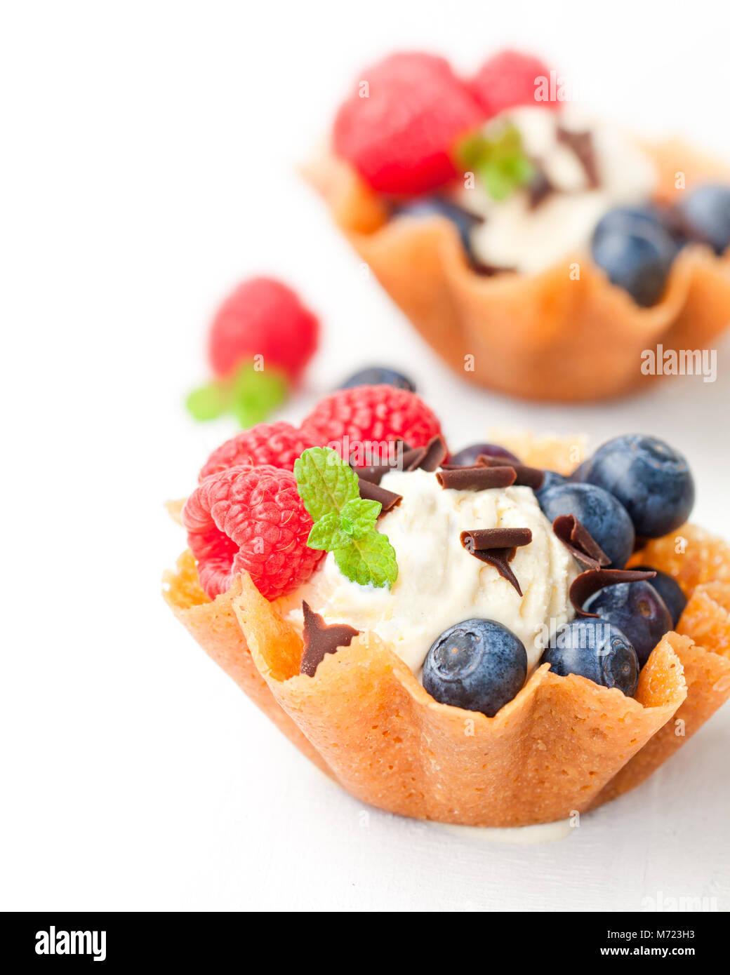 Il brandy scatta cesti con gelato e frutti di bosco su sfondo bianco Foto Stock