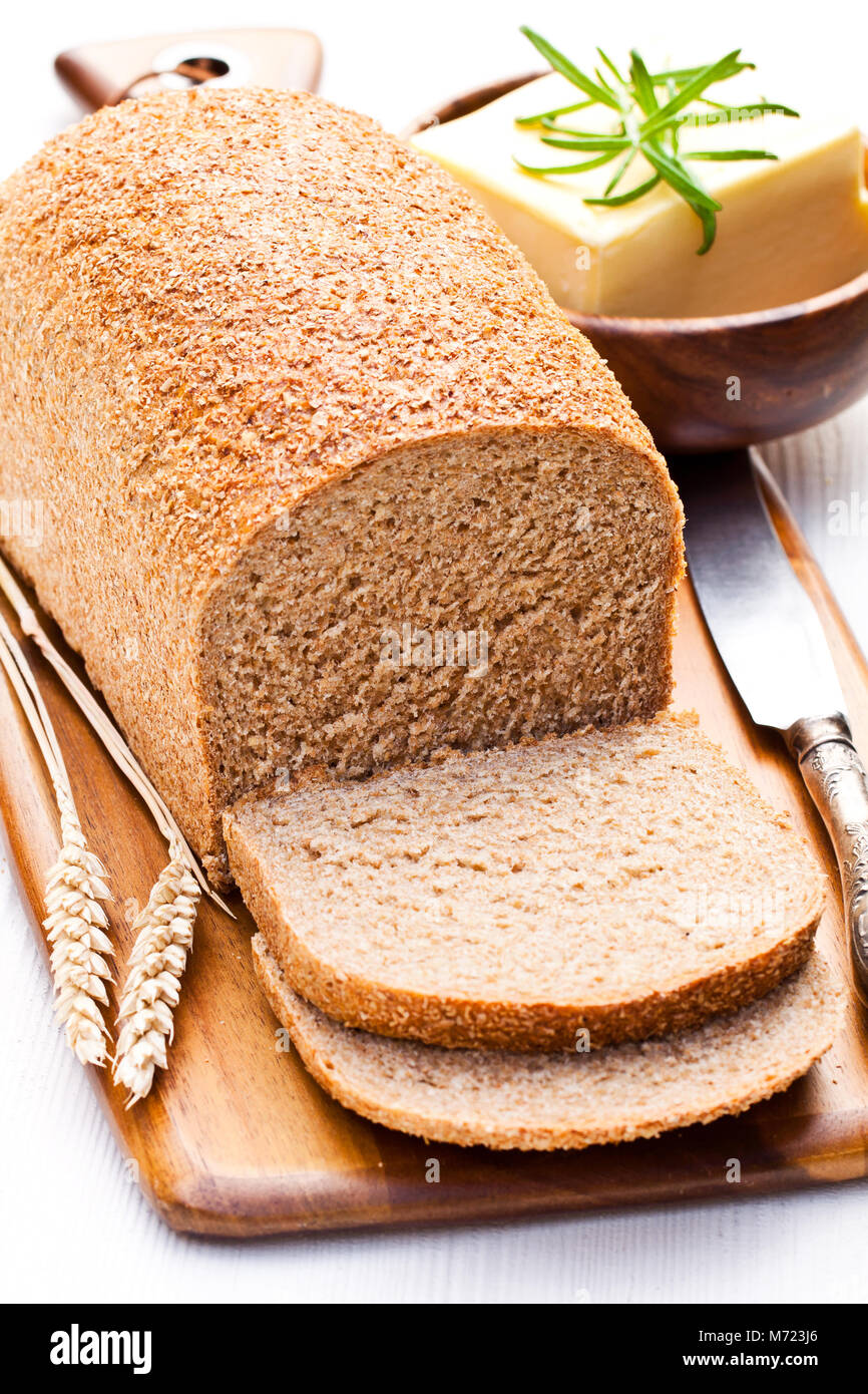 Fette di slow-biologico cotto al pane integrale con burro e rosmarino e spighe di grano Foto Stock