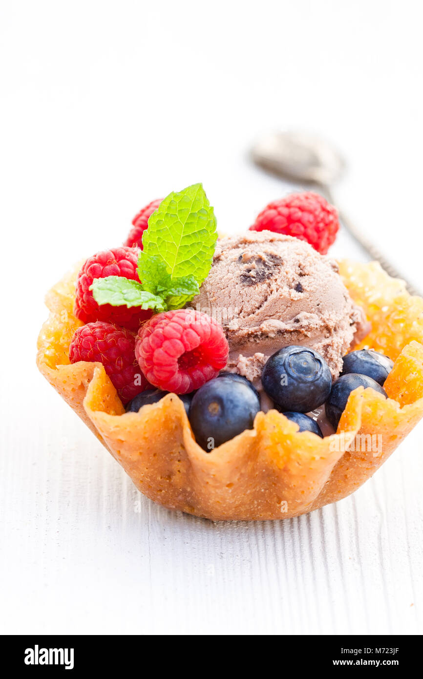 Il brandy scatta il cestello con il gelato al cioccolato e bacche di colore bianco su sfondo di legno Foto Stock