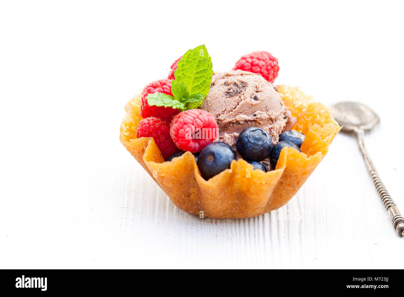Il brandy scatta il cestello con il gelato al cioccolato e bacche di colore bianco su sfondo di legno Foto Stock