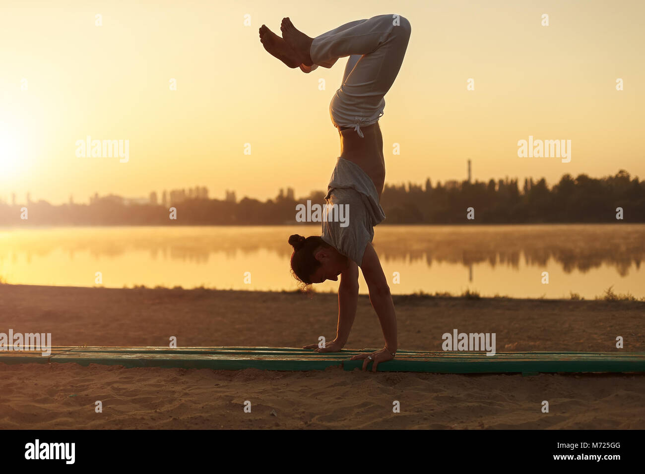 Concetto di persone, stile di vita e sport. Capoeira sulla spiaggia, vicino al lago nel parco un interprete, a sunrise. Casual Uomo atletico in pantaloni bianchi Foto Stock