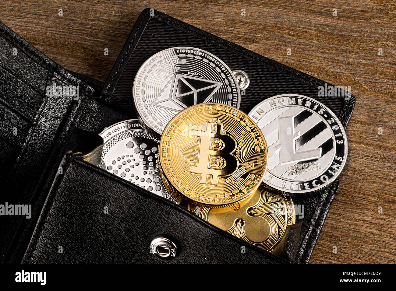 Crypto valuta moneta nel portafoglio in pelle su vasta in legno bitcoin sfondo ethereum litecoin iota ripple Foto Stock