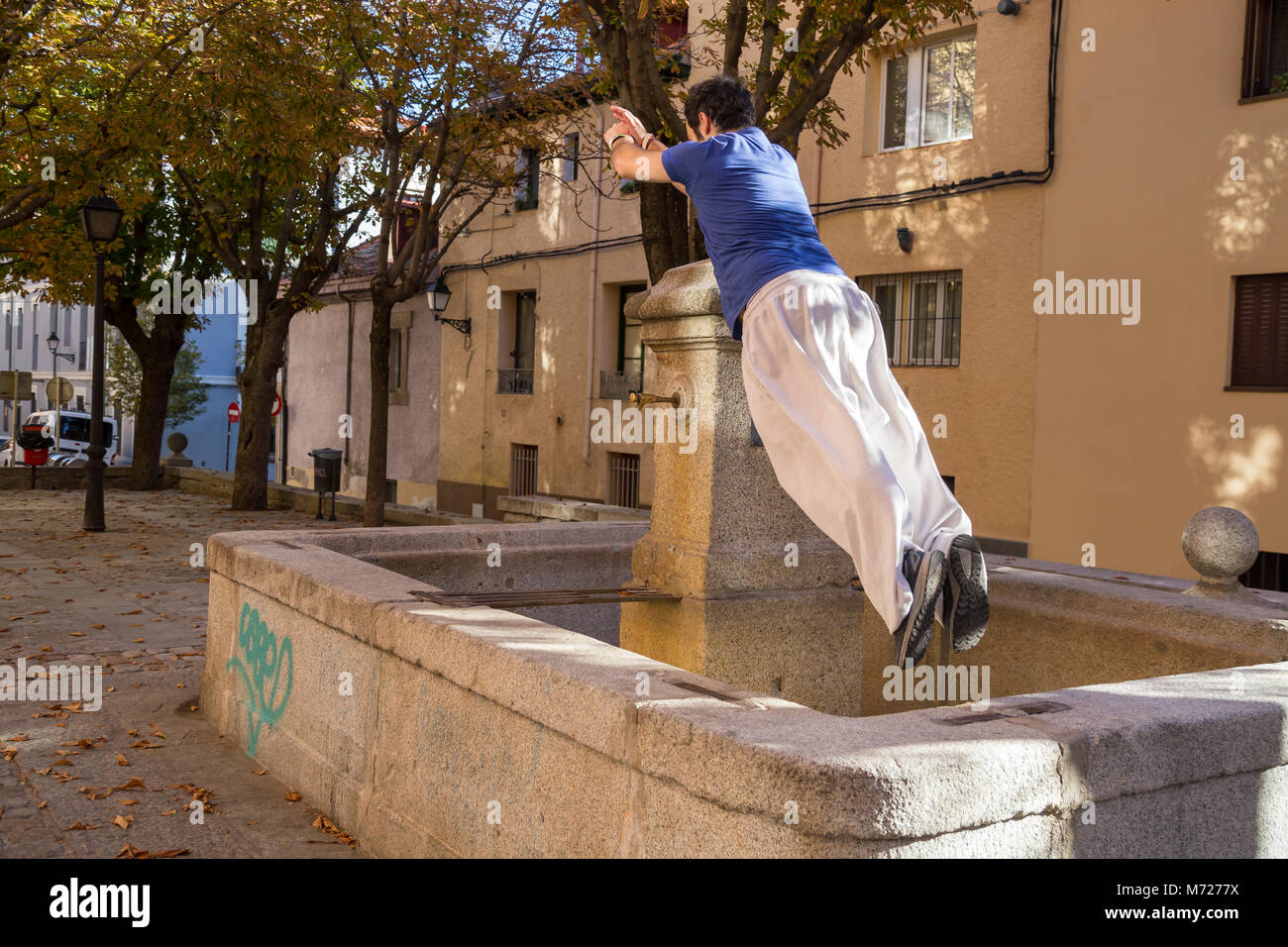 Giovane uomo che fa un impressionante salto parkour sulla strada. Foto Stock