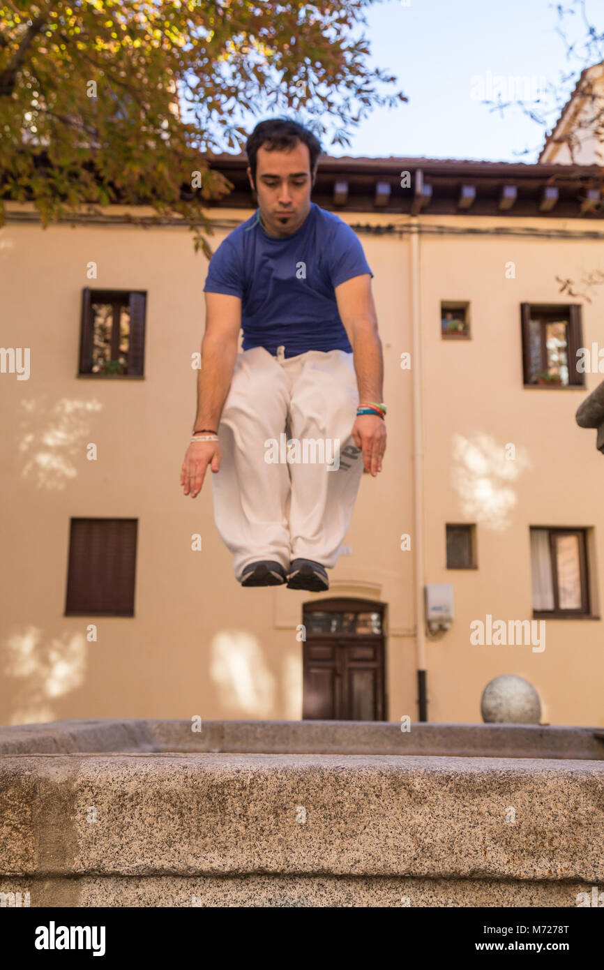 Giovane uomo che fa un impressionante salto parkour sulla strada. Foto Stock