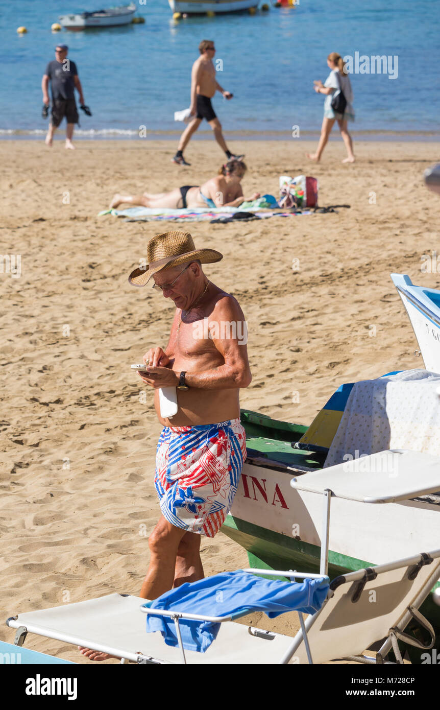 Uomo anziano utilizzando il telefono cellulare sulla spiaggia Foto Stock