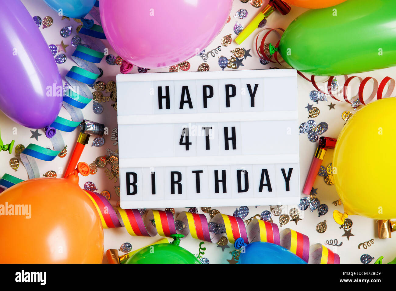 Felice quarto compleanno celebrazione messaggio su un lightbox con palloncini e coriandoli Foto Stock