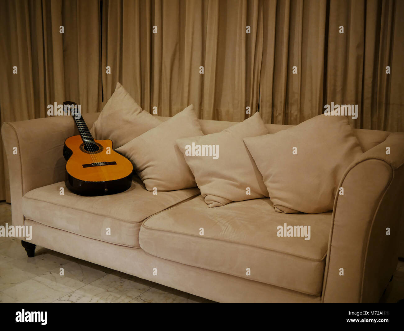 Una chitarra in appoggio su un divano nel soggiorno dopo essere stato utilizzato in una registrazione Foto Stock