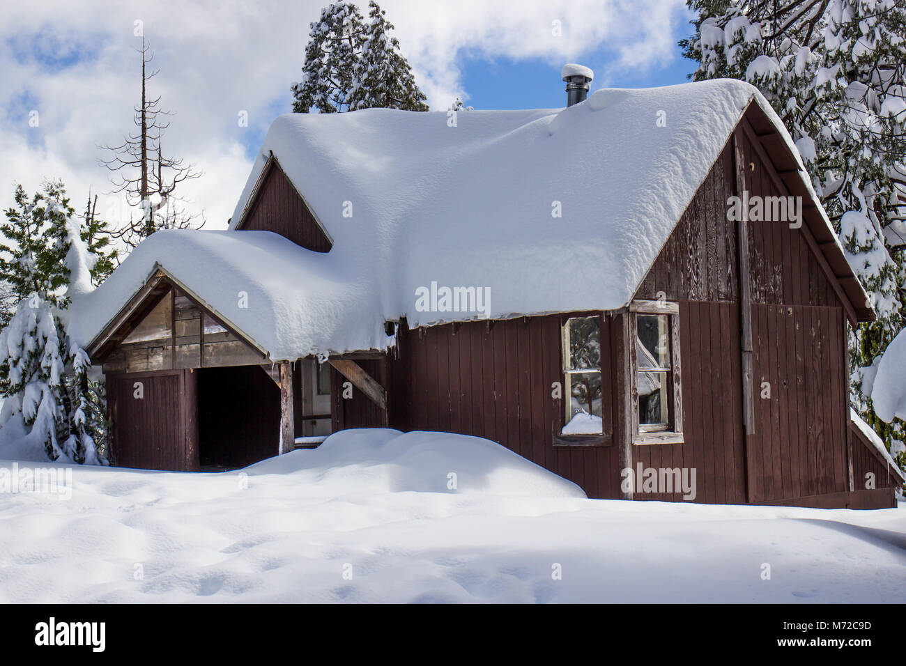 Cabina in legno con derive di neve sul tetto Foto Stock