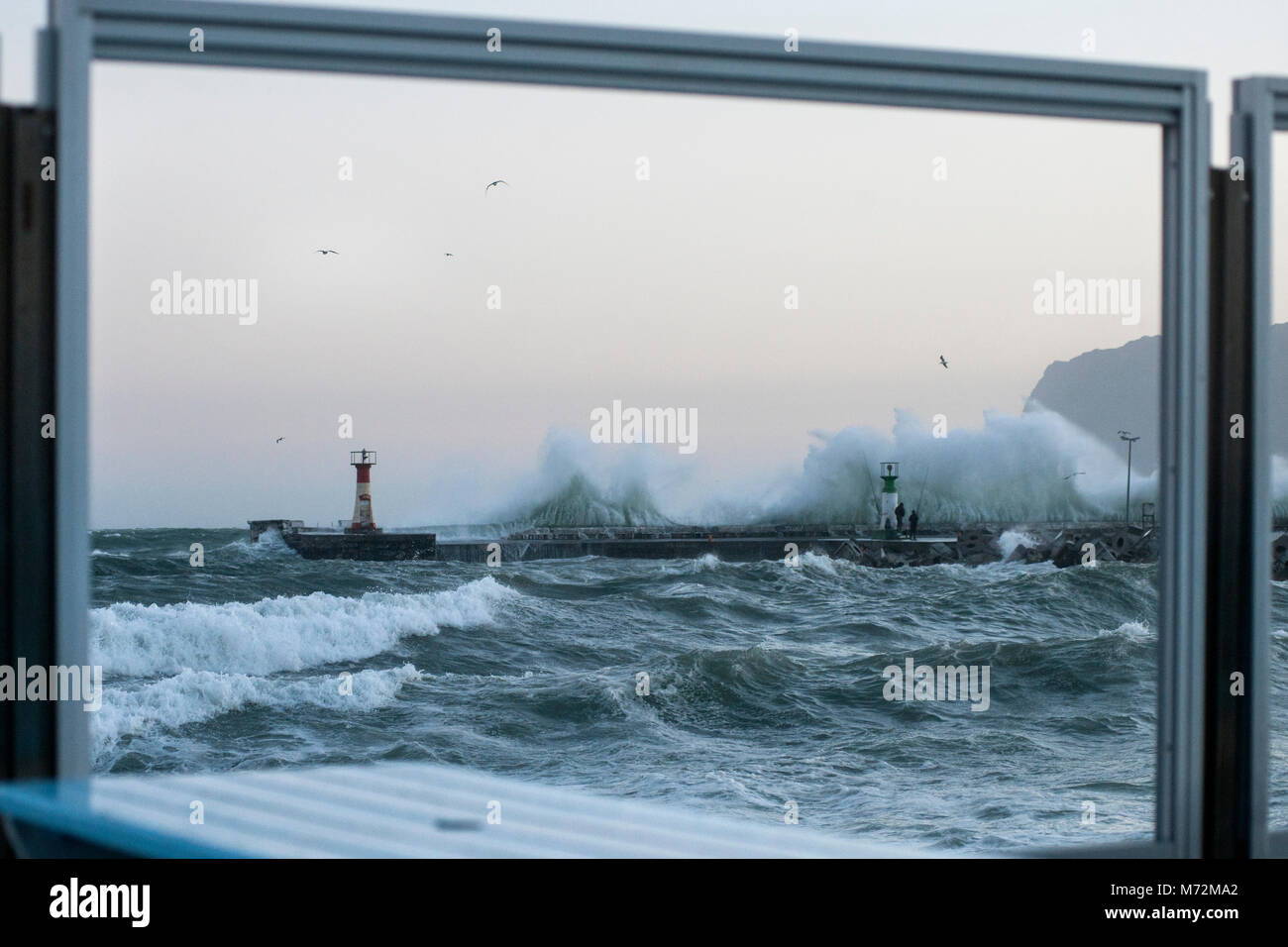 I pescatori sfidando le onde enormi che si sono visti qui di schiantarsi contro il frangiflutti di Kalk Bay Harbor in Cape Town, Sud Africa. La scena è p. Foto Stock
