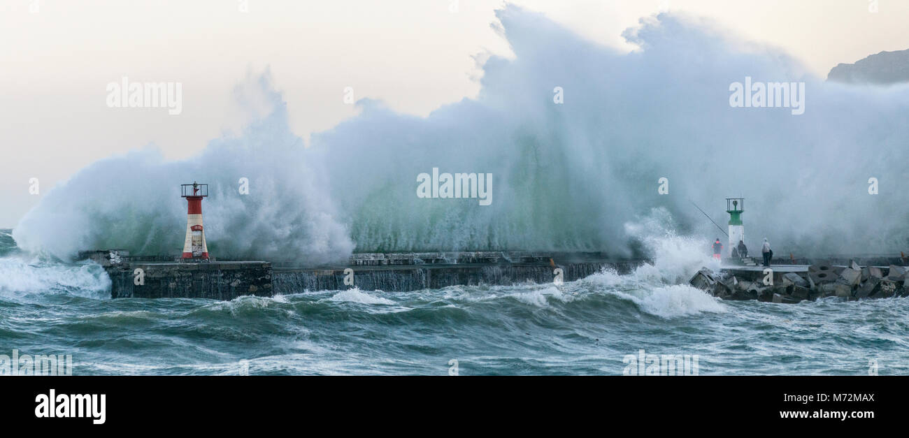 I pescatori sfidando le onde enormi che si sono visti qui di schiantarsi contro il frangiflutti di Kalk Bay Harbor in Cape Town, Sud Africa. Foto Stock