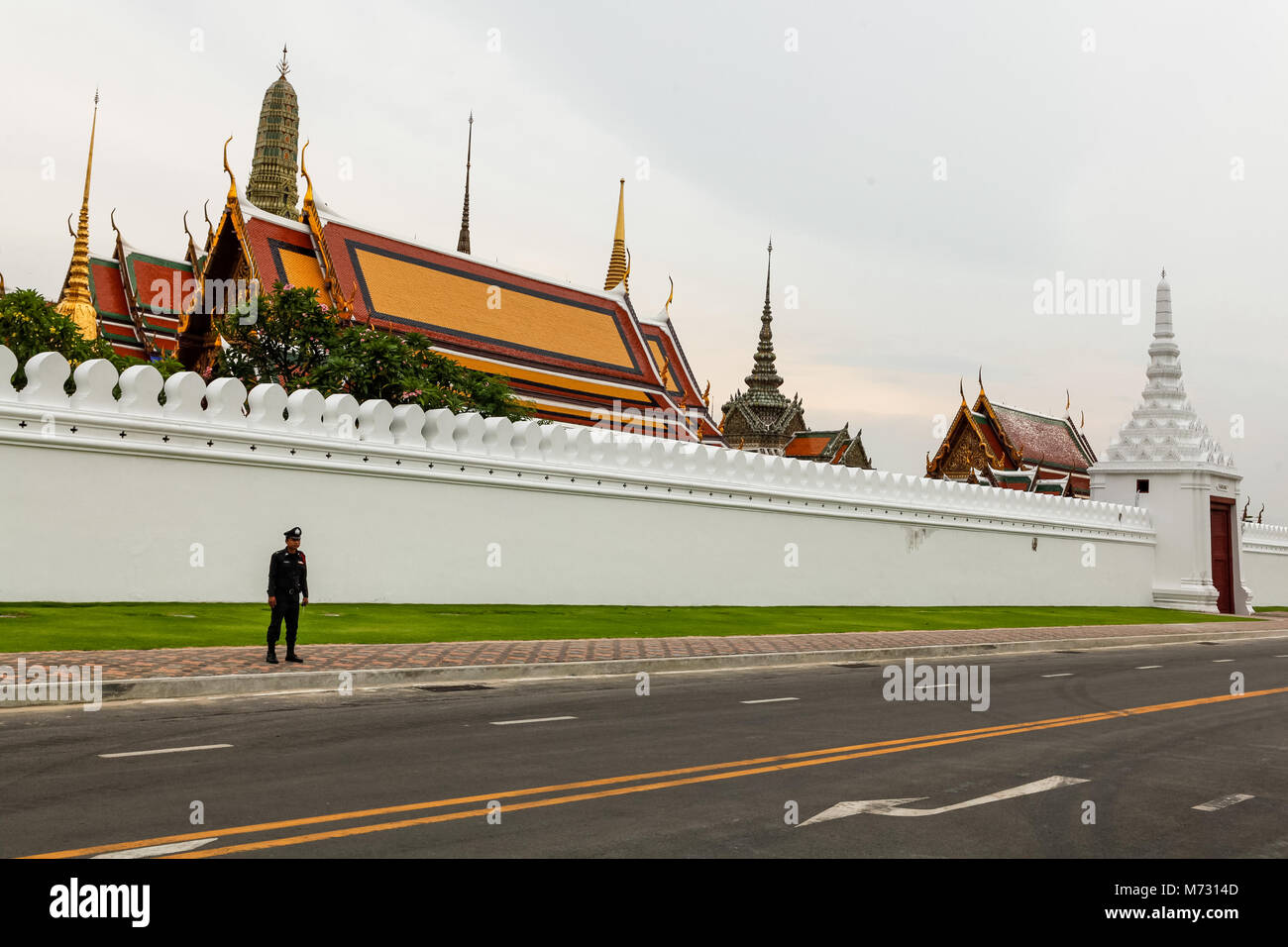 Silhouette di una thailandese funzionario di polizia contro il muro bianco del Grand Palace, con i templi e stupa in background Foto Stock