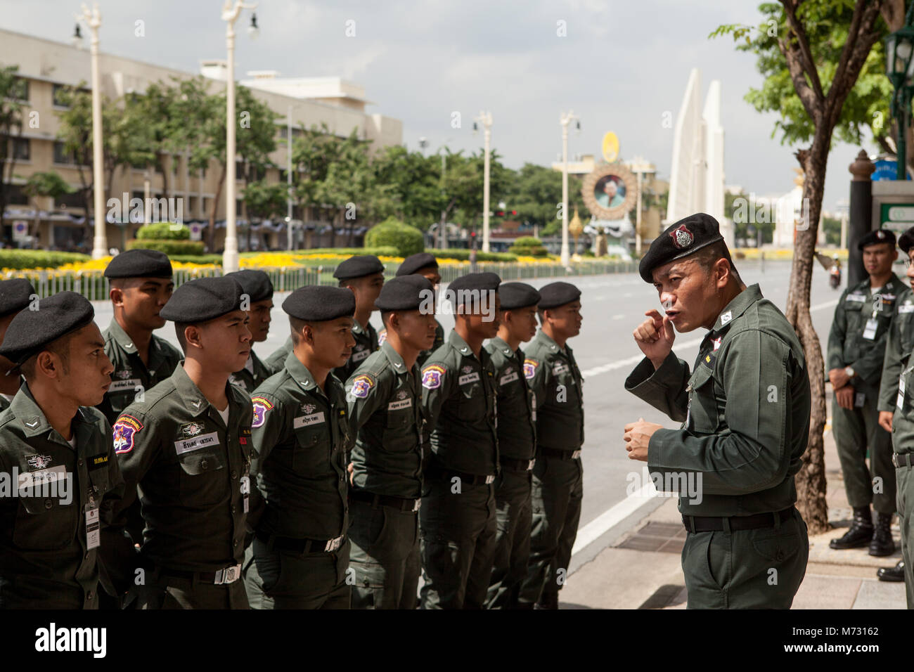 Soldati tailandesi in linea ascoltando il capitano Ratchadamnoen Road di Bangkok il giorno del Royal cremazione, con la democrazia un monumento in retro Foto Stock