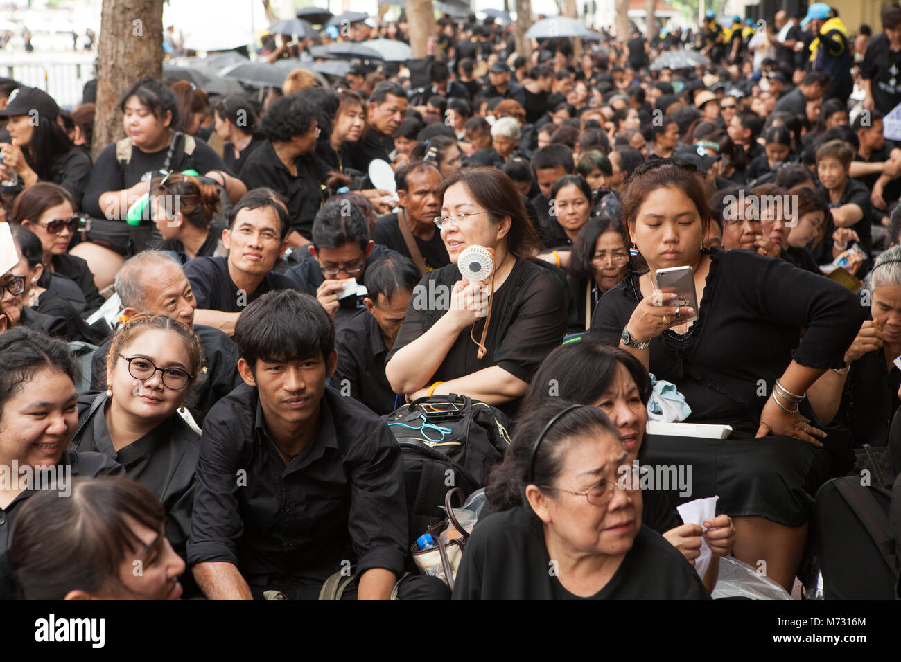 La gente vestita di nero in lutto per i vestiti, in attesa di Ratchadamnoen Road di Bangkok per assistere al Royal cremazione del Thai Re Bhumibol Adulyadej Foto Stock