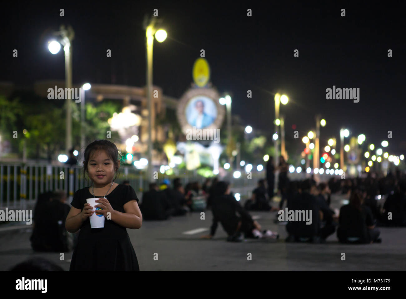 Sorridente di capretto e persone in Ratchadamnoen Road dopo la cremazione reale, di notte, immagine del Re Tailandese in background. Bangkok, 26 Ottobre 2017 Foto Stock
