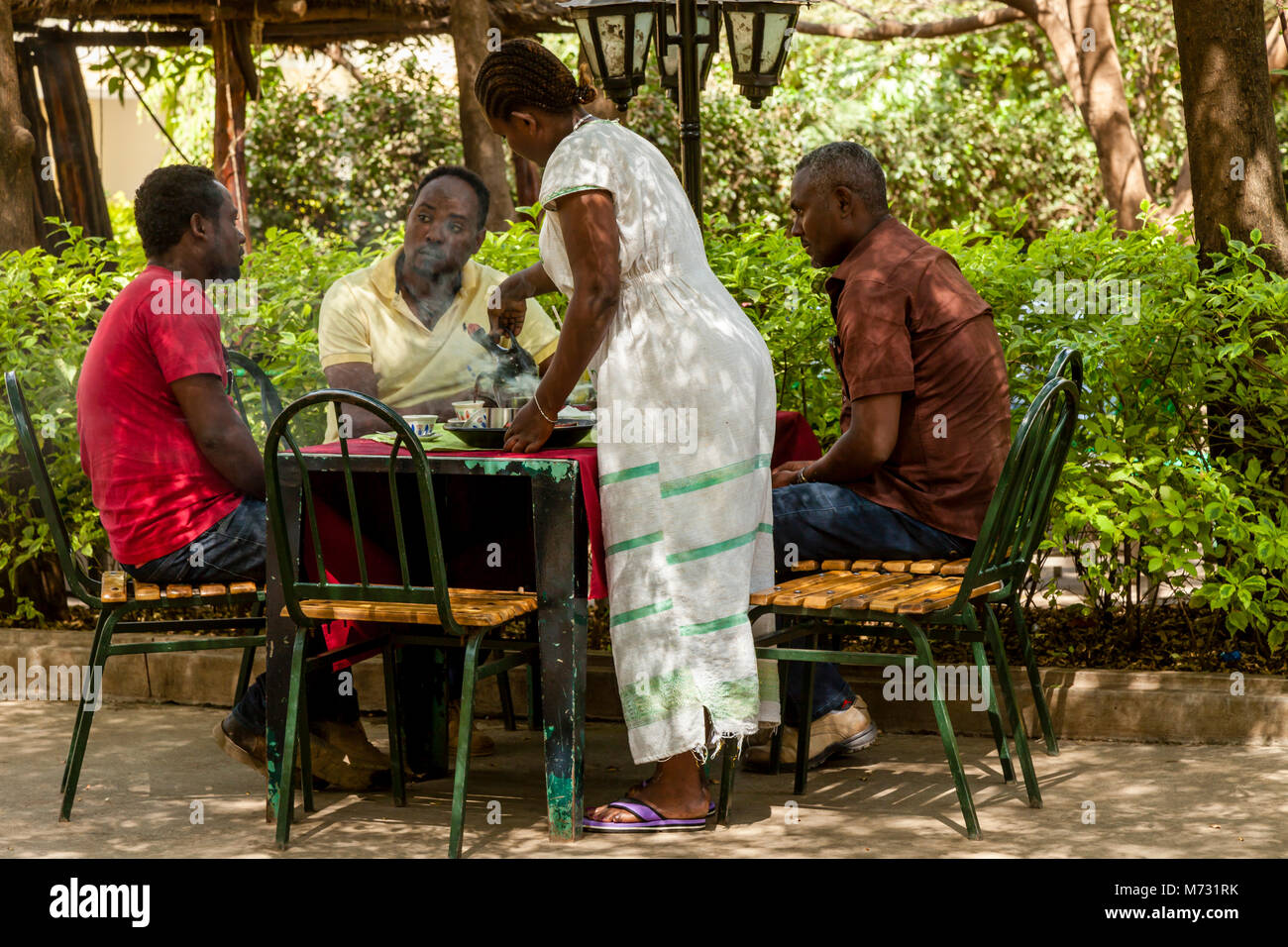 Una donna che serve il caffè per un gruppo di uomini in un Cafe, Arba Minch, Gamo Gofa Zona, Etiopia Foto Stock