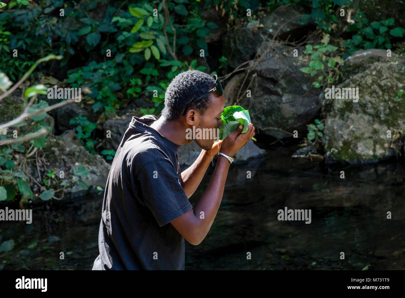 Un giovane uomo beve l'acqua dal quaranta molle nel Nechisar National Park, Arba Minch, Etiopia Foto Stock