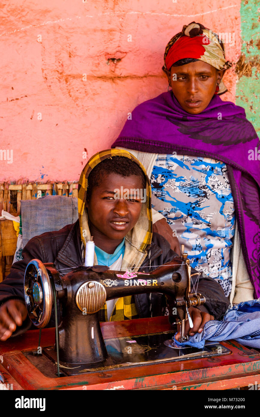Un giovane uomo che ripara i vestiti utilizzando una vecchia macchina da cucire presso il mercato del sabato nel villaggio di Dorze di Chencha, Gamo Gofa Zona, Etiopia Foto Stock