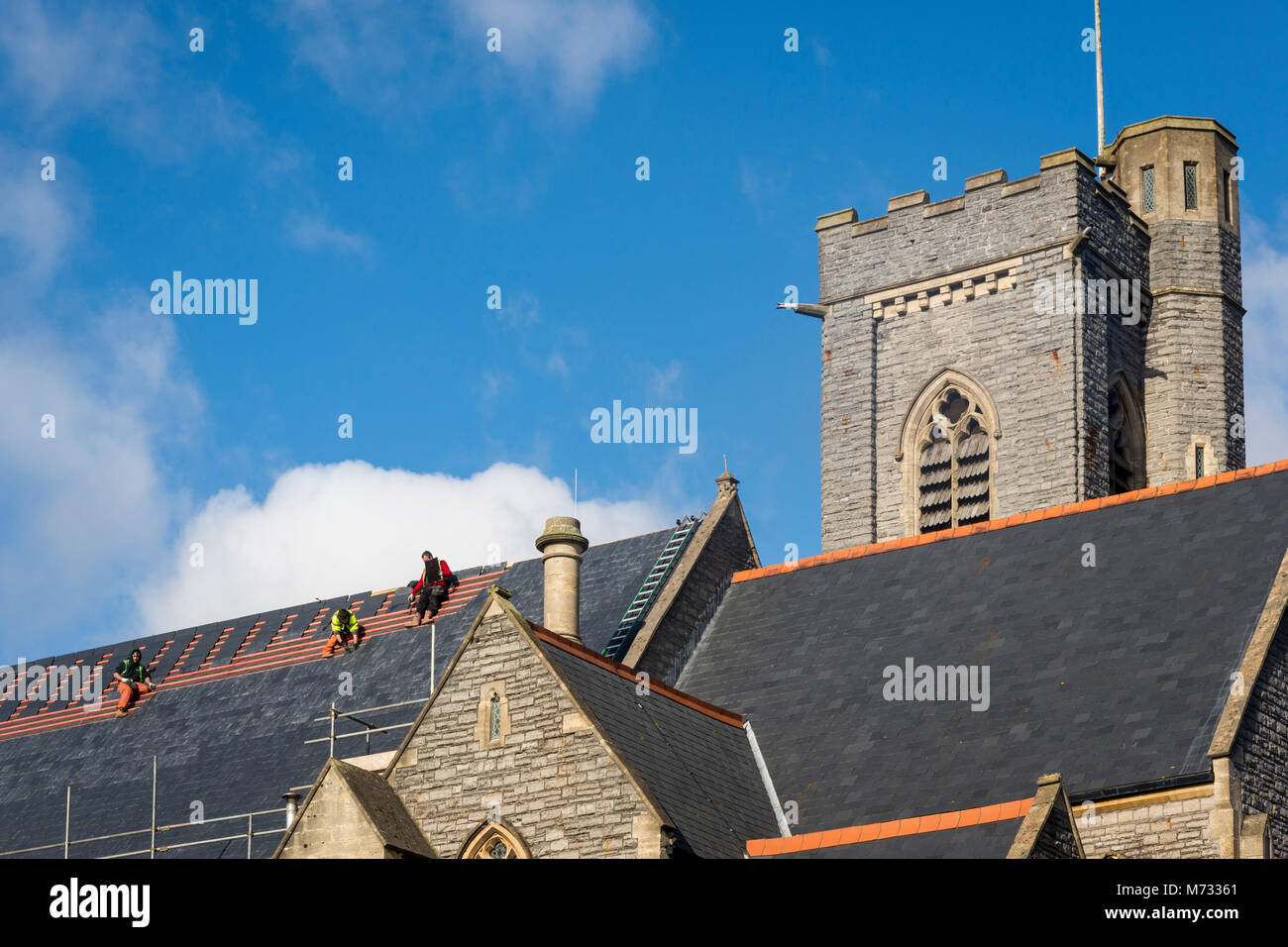 Il fissaggio del tetto, mentre il sole risplende. Le falde del tetto della chiesa di Tutti i Santi di Barry Wales essendo riparata in una luminosa giornata di sole sotto un cielo blu Foto Stock