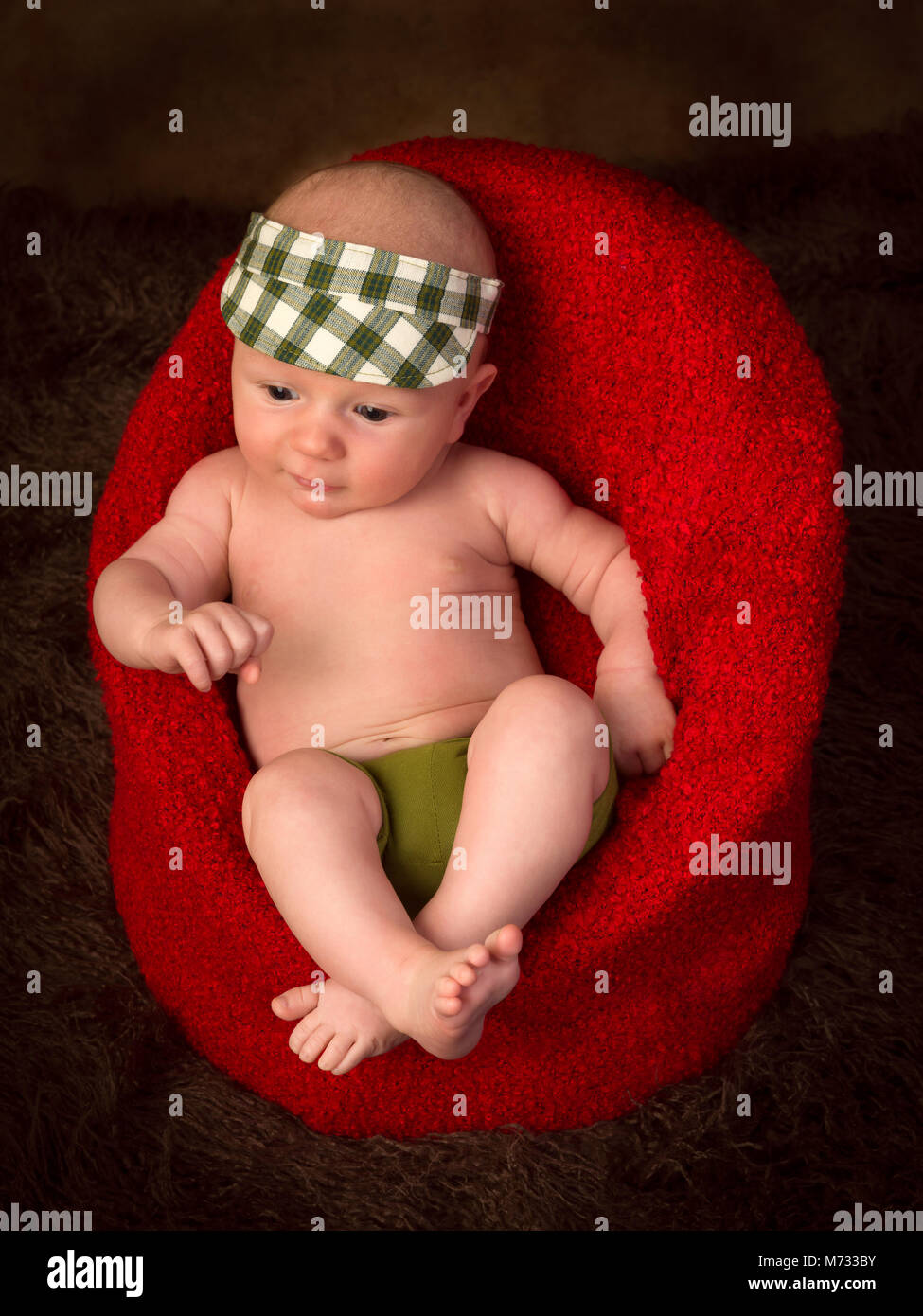 Immagine divertente di un 7 settimane vecchio piccolo bambino seduto in una confortevole poltrona Foto Stock