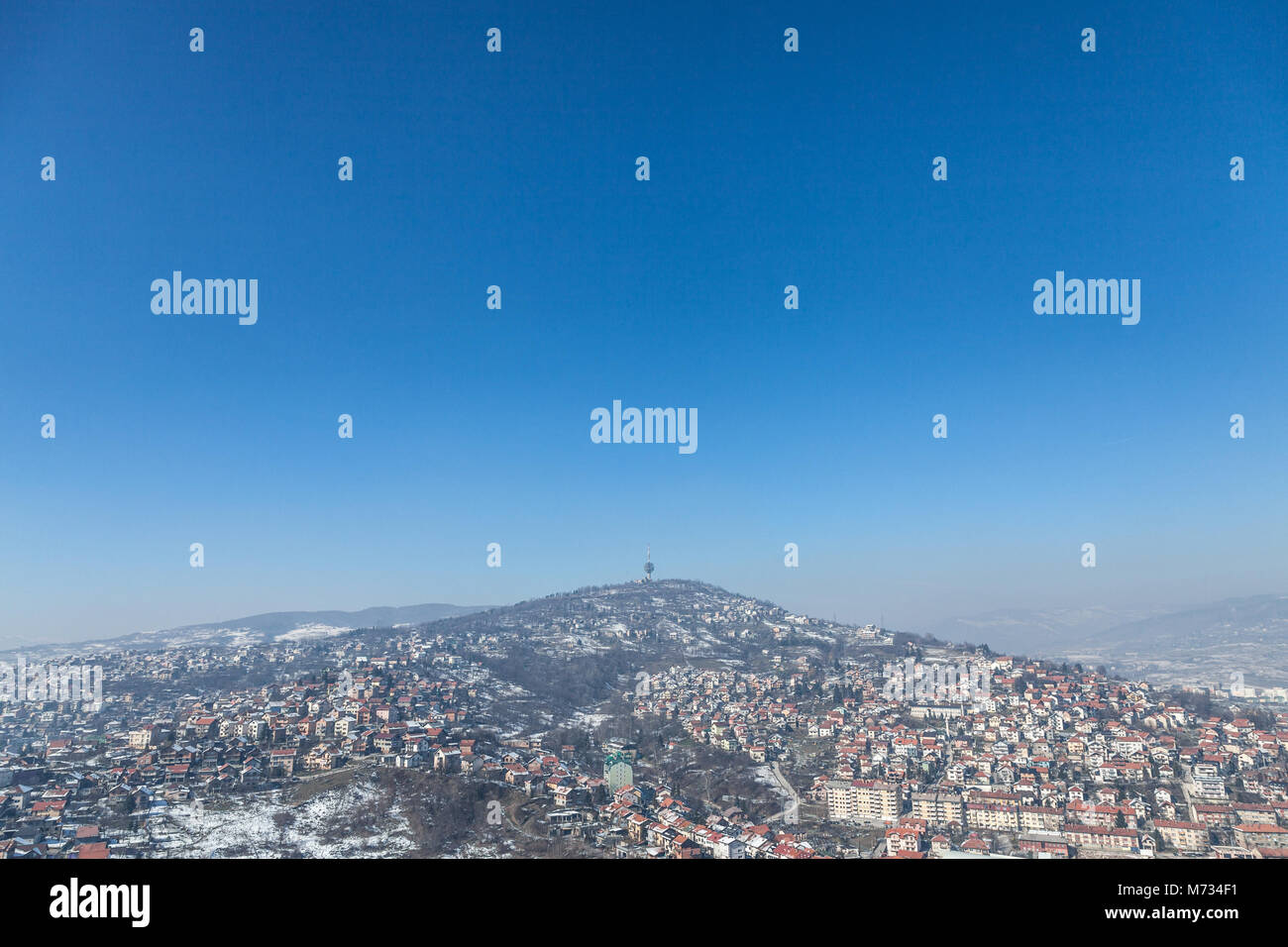 Vista aerea delle colline della periferia di Sarajevo, Bosnia ed Erzegovina durante un inverno freddo pomeriggio di neve che ricoprono tutto. La torre della TV di t Foto Stock