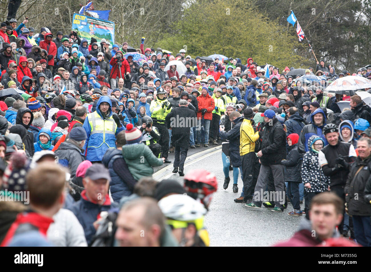 Tour de Yorkshire 2016 uno spettatore nel tappo piatto scarpe e soprabito corre fino Sutton Bank per la delizia del specatator attesa per il tour de yorkshire Foto Stock