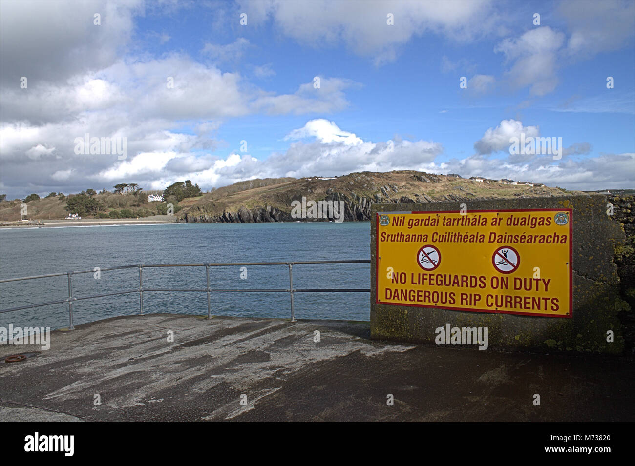 Pericolo maree Rip sign in inglese e in gaelico. Il segno è alla fine di un pontile in Rossbarbery, Irlanda, dove le correnti muovere davvero!! Foto Stock