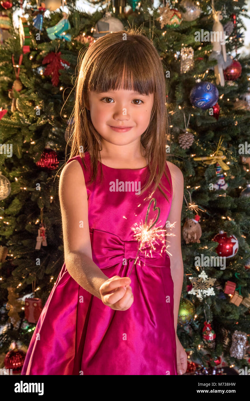 Bambina di cinque anni tenendo un a forma di cuore ad sparkler alla vigilia di Natale Foto Stock