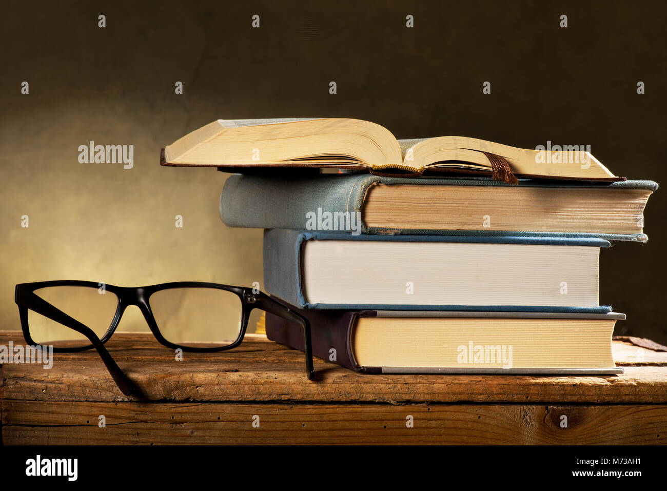Libro aperto con gli occhiali da lettura sullo sfondo scuro Foto Stock