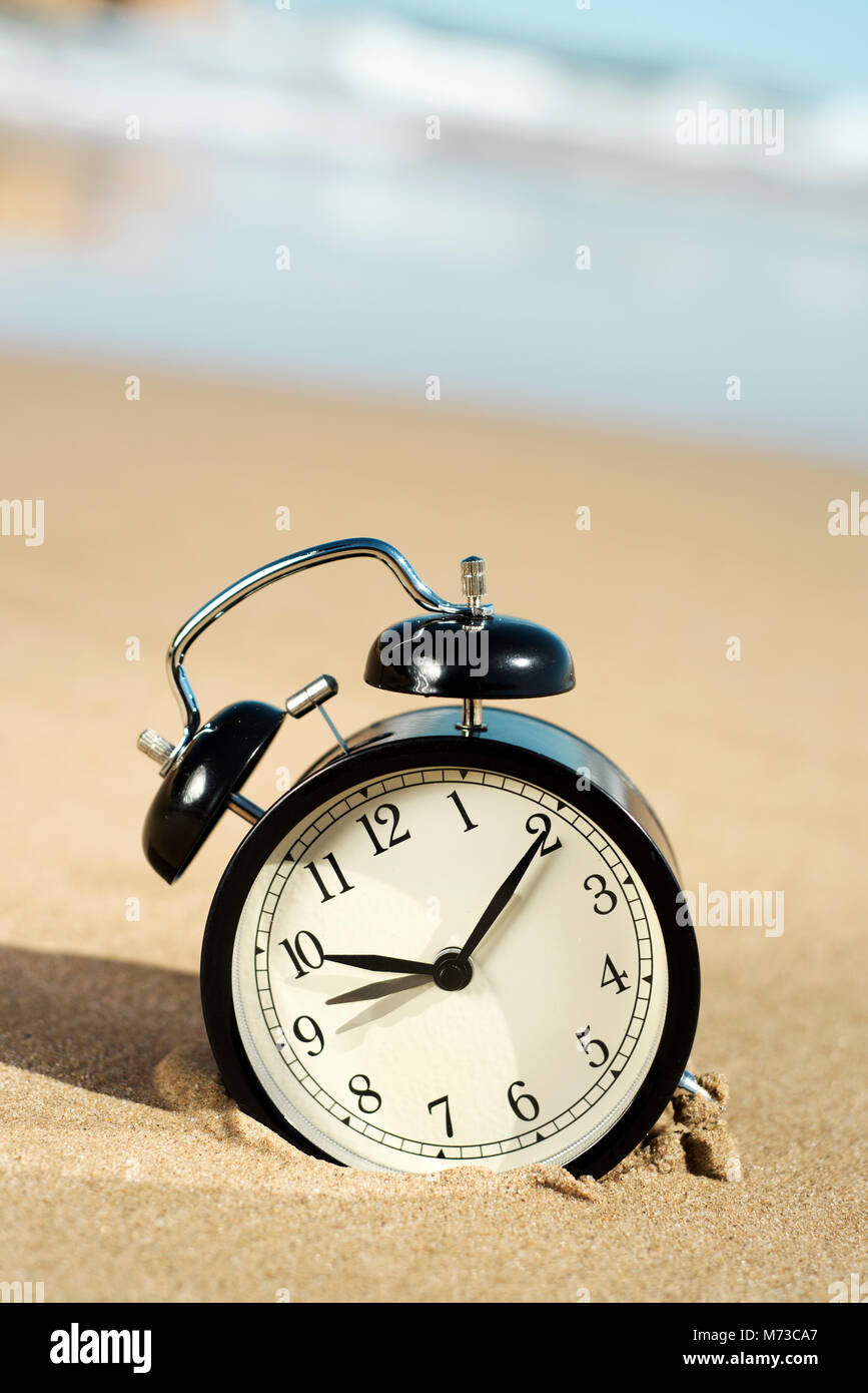 Primo piano di un allarme sulla sabbia della spiaggia, regolando il tempo in avanti o indietro di un'ora, all'inizio o alla fine dell'ora legale Foto Stock