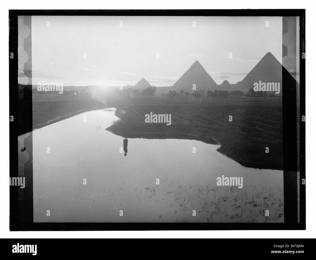 Questa immagine raffigura una scena serale al Cairo, in Egitto, che mostra il fiume Nilo che trabocca vicino alle piramidi. La fotografia cattura la bellezza naturale e storica della zona. Foto Stock