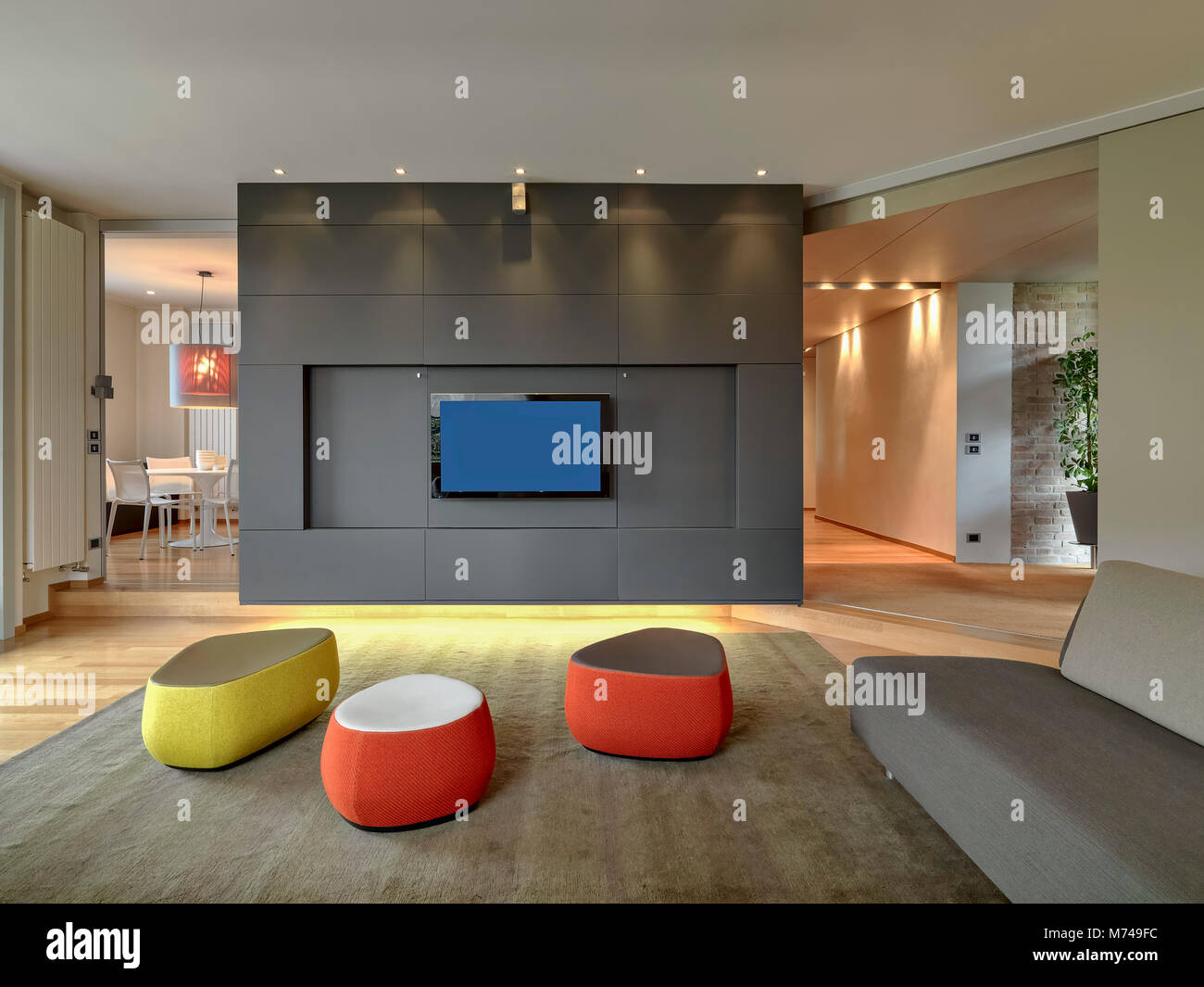 Scatti di interni di un soggiorno moderno con il rosso e il giallo del poggiapiedi, moquette grigio e divano, il pavimento è in legno di tutte si affacciano sul dinin Foto Stock