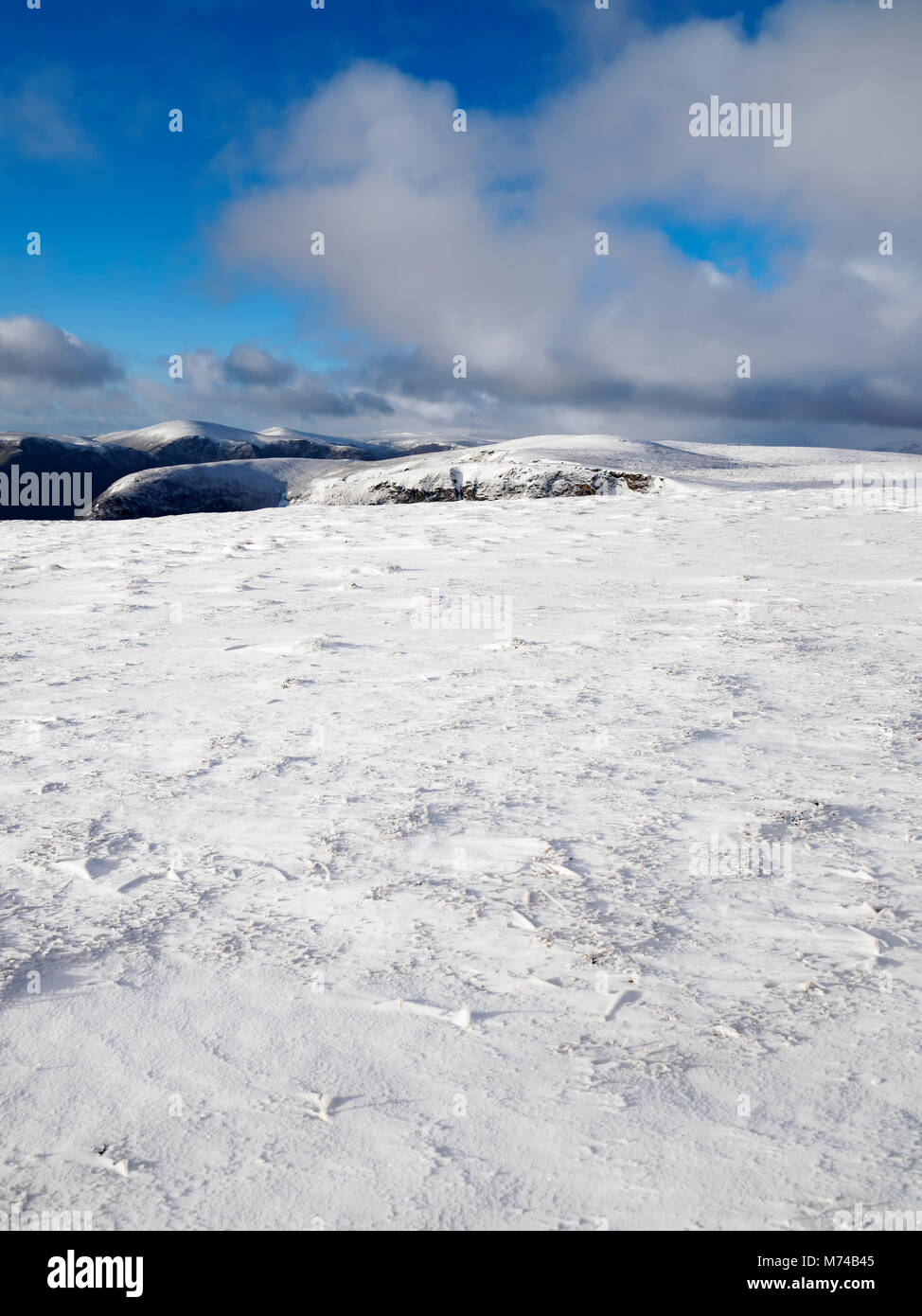 Guardando oltre la parte superiore del Loch Brandy dalla coperta di neve pendici di una verde collina di Glen Clova, Angus. Foto Stock