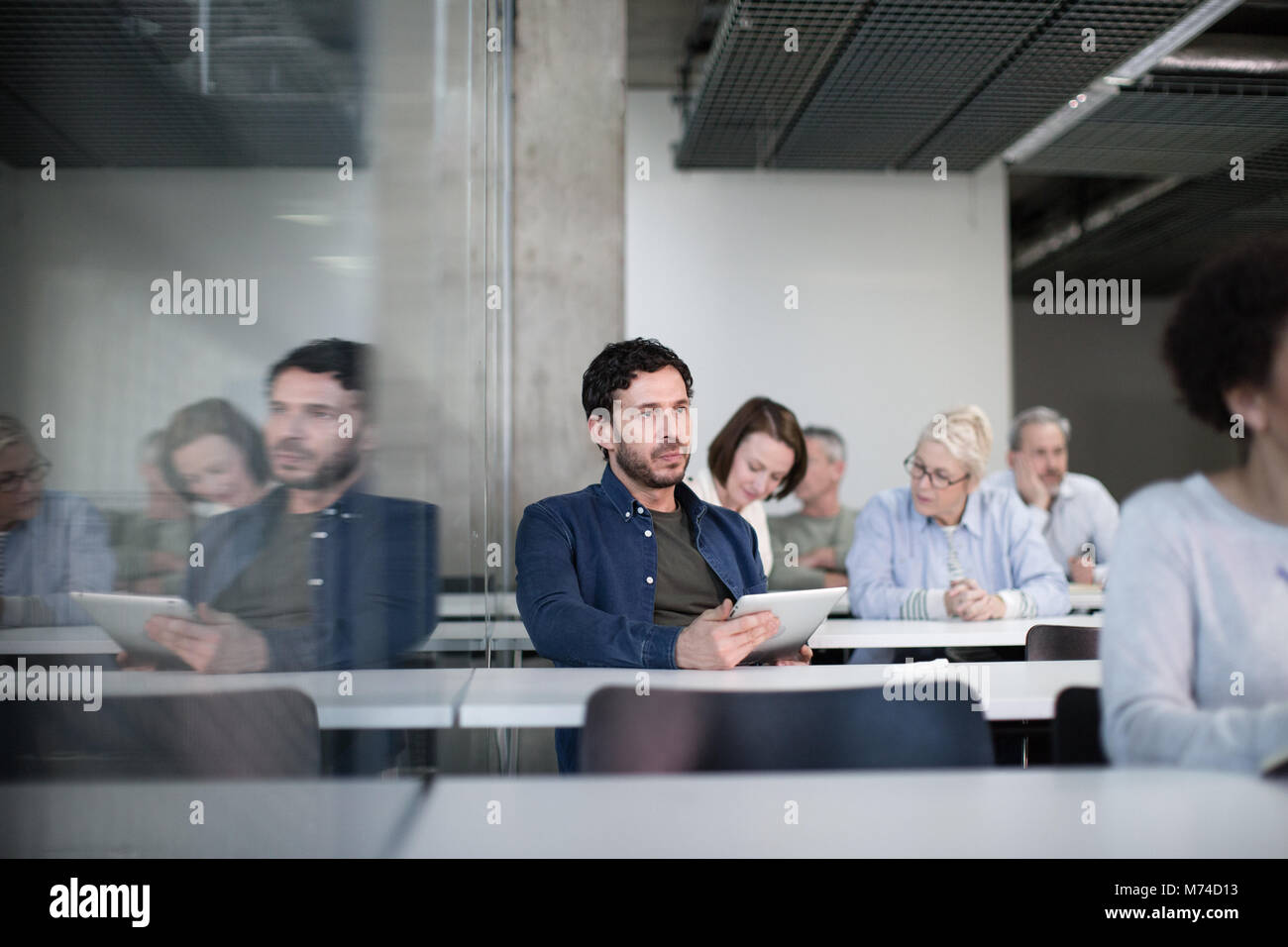 Coppia studente prendendo appunti sulla tavoletta digitale in una lezione Foto Stock